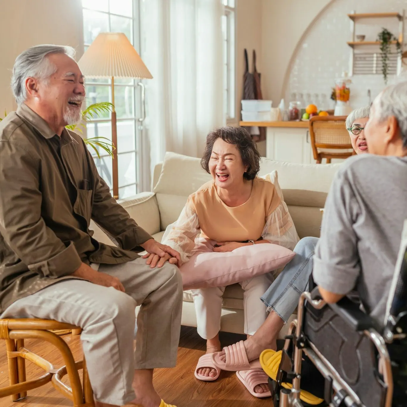 Older people chatting and laughing together in a bright living room